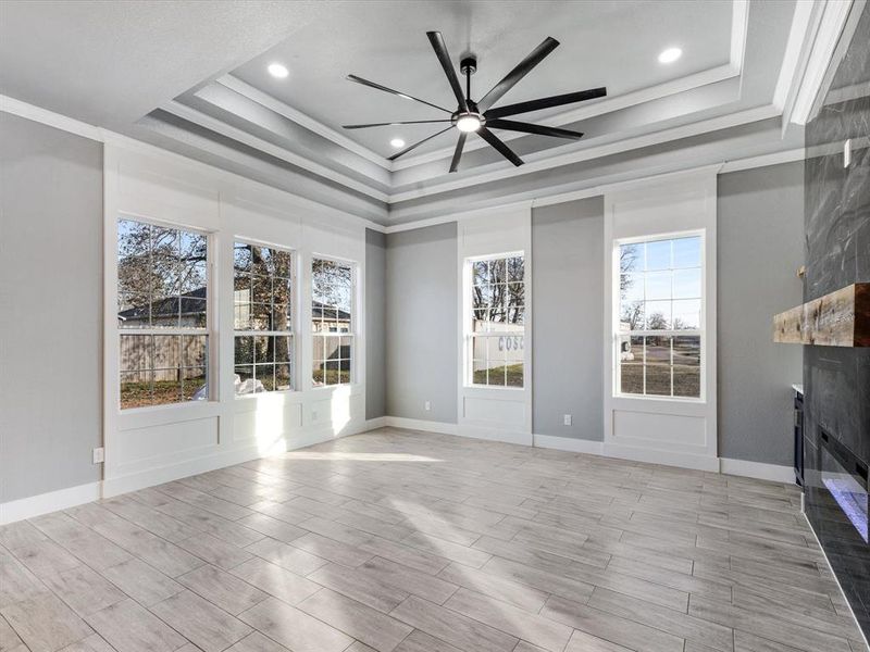 Unfurnished living room with a ceiling fan, a large fireplace, wood finish floors, crown molding, and recessed lighting Unfurnished living room with a ceiling fan, a large fireplace, wood finish floors, crown molding, and recessed lighting