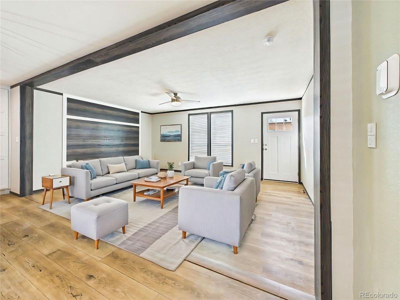 (Virtually Staged) – Staged living space illustrating layout potential with comfortable seating arrangement and a bright, welcoming atmosphere.