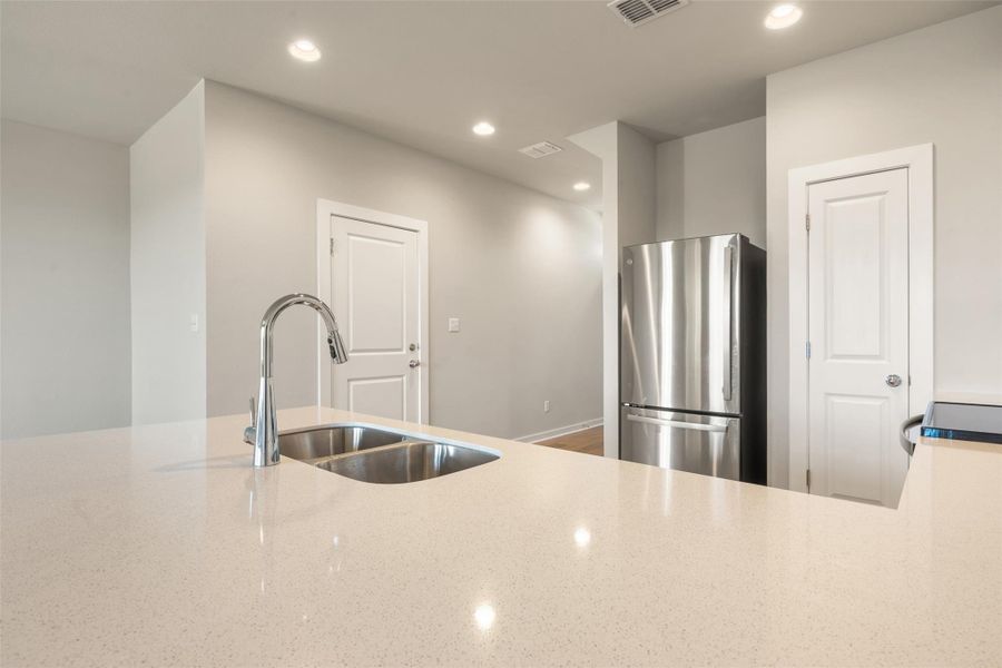 Kitchen featuring freestanding refrigerator, recessed lighting, light stone counters, and black electric range