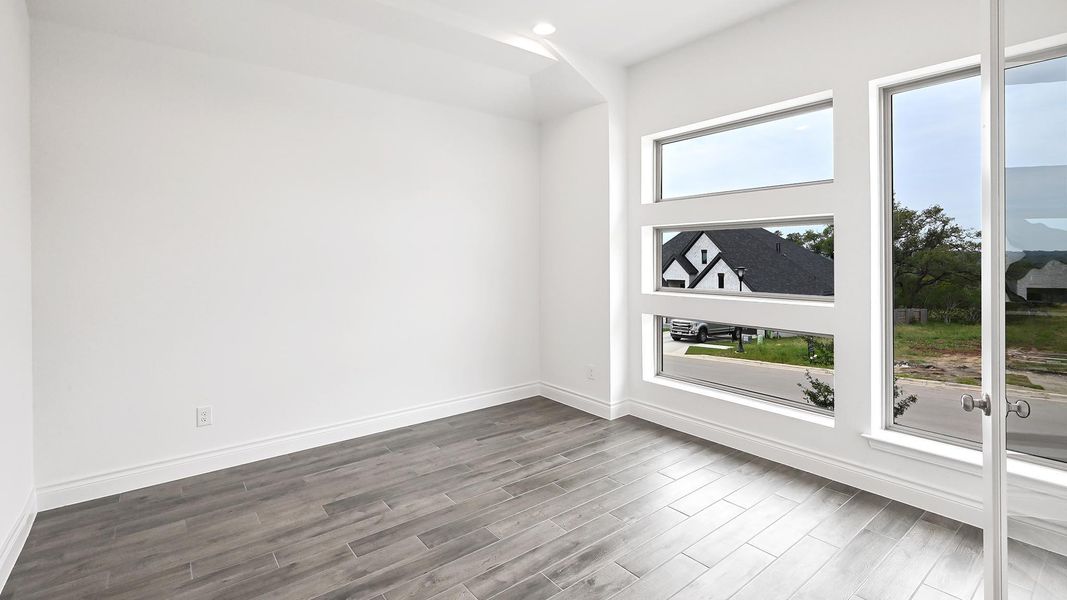Empty room with dark wood-style flooring, baseboards, and recessed lighting Empty room with dark wood-style flooring, baseboards, and recessed lighting