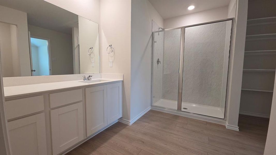 Bathroom featuring a long vanity with dual sinks, white cabinetry, and a large mirror