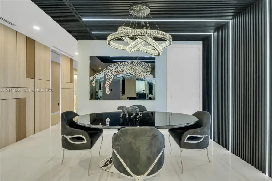 Contemporary space featuring a slatted black ceiling and wall accent, integrated linear LED lighting, large-format tile flooring, and a multi-tiered crystal ring chandelier Contemporary space featuring a slatted black ceiling and wall accent, integrated linear LED lighting, large-format tile flooring, and a multi-tiered crystal ring chandelier