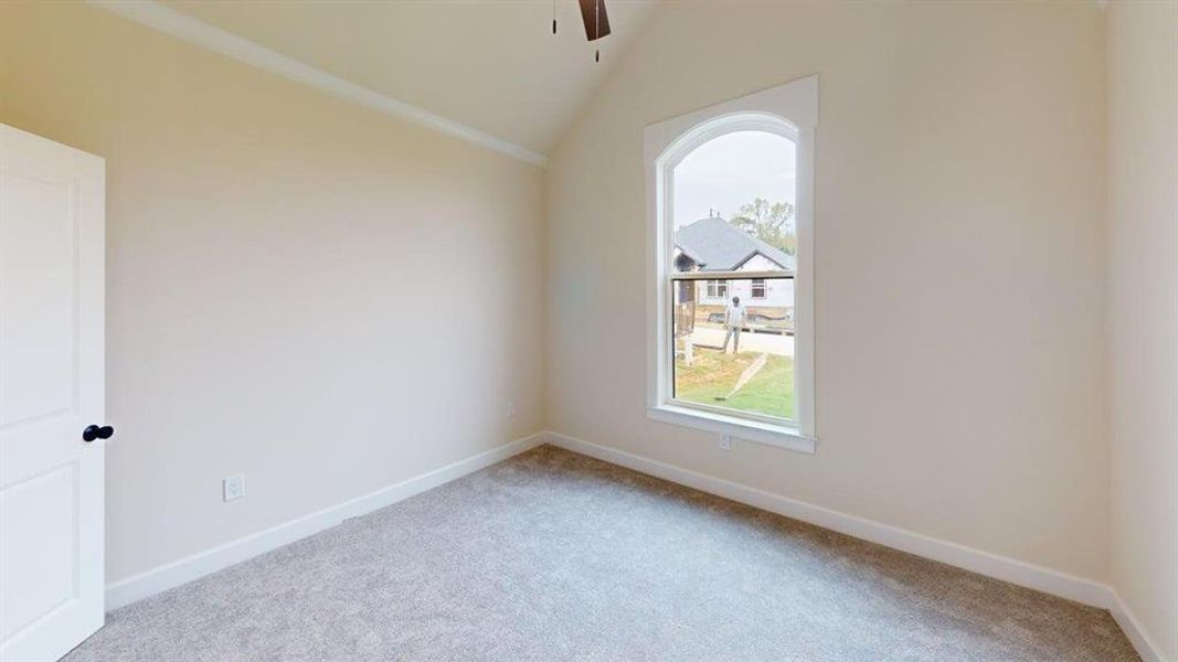 Carpeted spare room with ceiling fan and vaulted ceiling