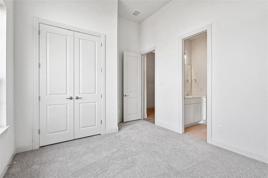 Unfurnished bedroom with light colored carpet, a closet, and ensuite bath