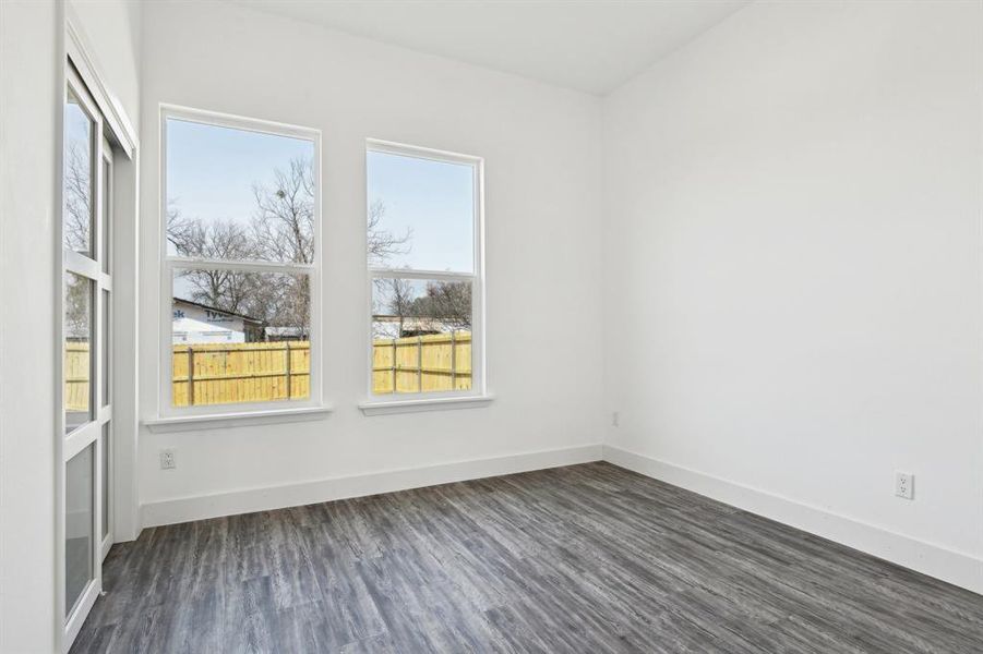 Empty room featuring dark wood-style flooring and baseboards