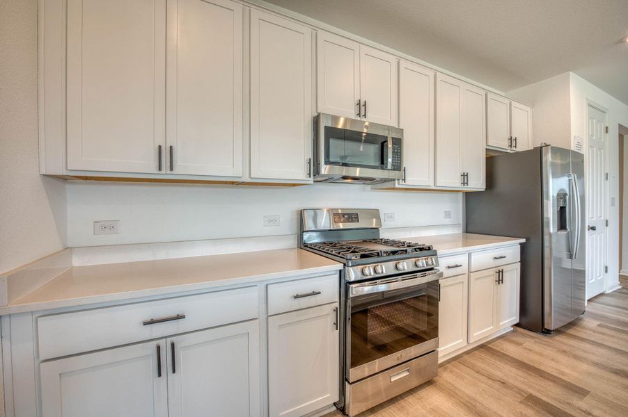 Gleaming stone countertops and stainless steel appliances maximize functionality in this culinary space.