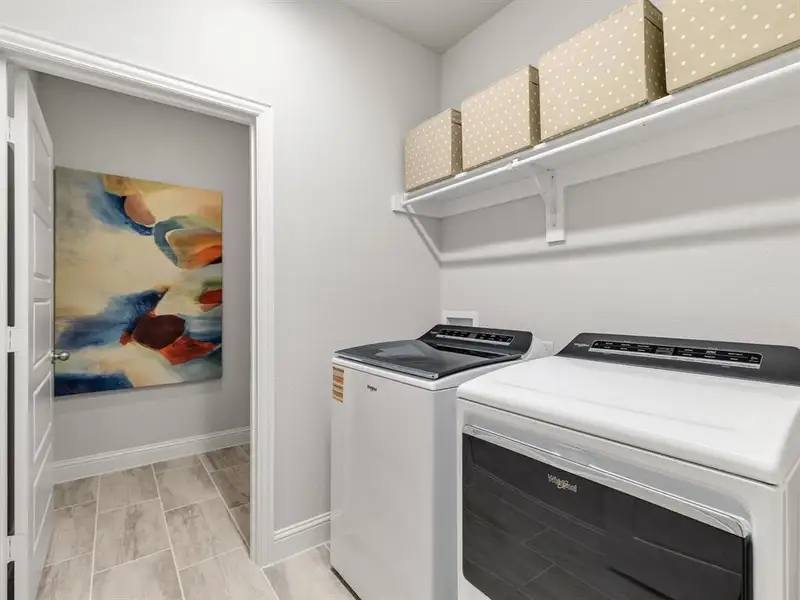 Dedicated utility room features durable built-in storage shelving and a convenient overhead drip-dry clothes hanging area.