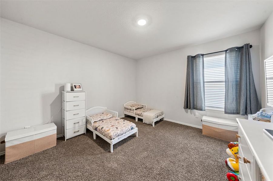 Bedroom featuring dark colored carpet and a nursery area