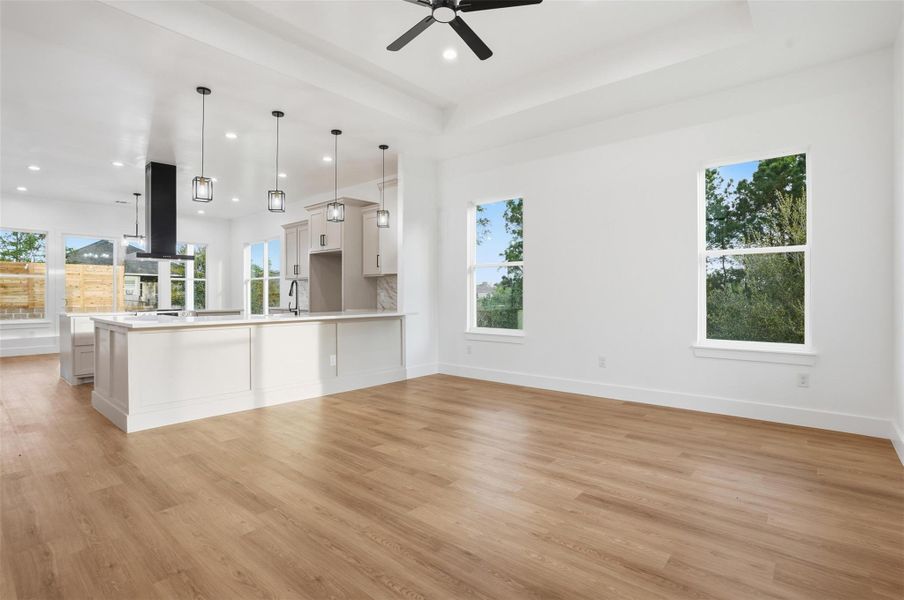 Kitchen with open floor plan, light countertops, a peninsula, light wood finished floors, and a tray ceiling