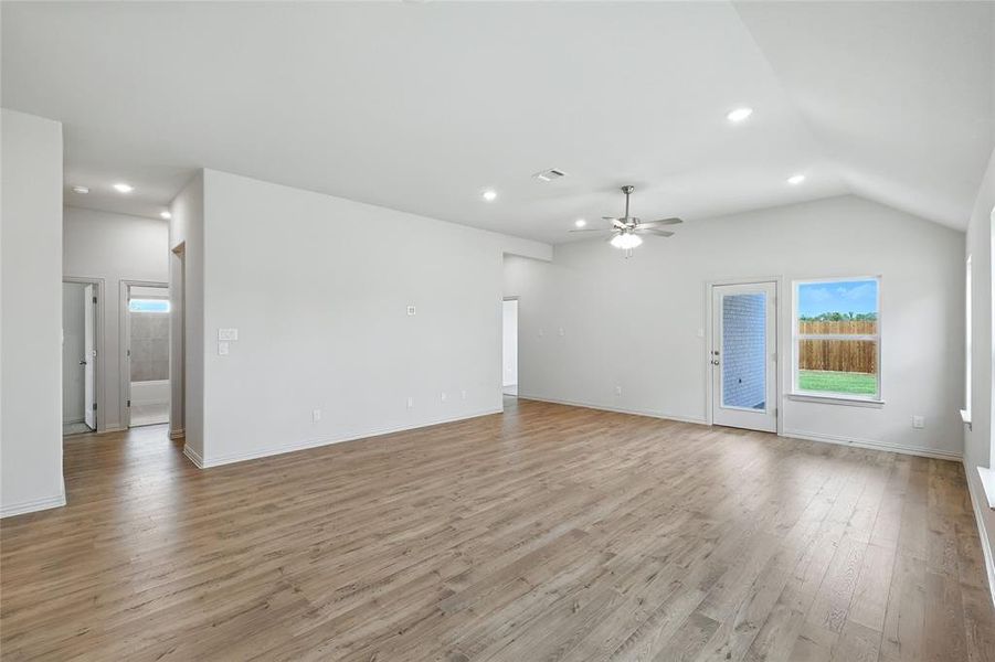 Unfurnished living room featuring light wood finished floors, recessed lighting, vaulted ceiling, and ceiling fan Unfurnished living room featuring light wood finished floors, recessed lighting, vaulted ceiling, and ceiling fan