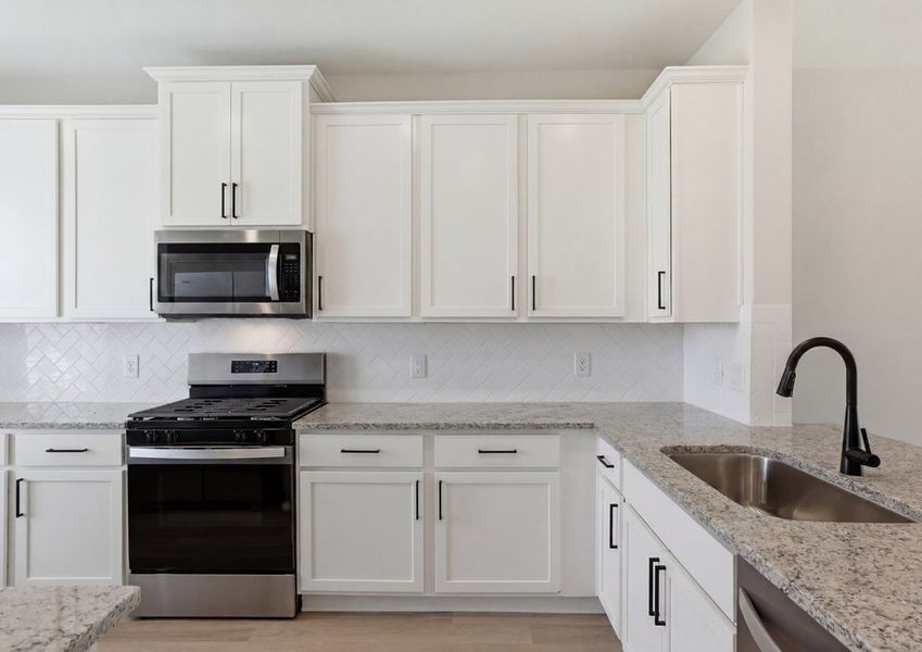 Kitchen featuring white cabinetry, granite countertops, and a stainless range and microwave.