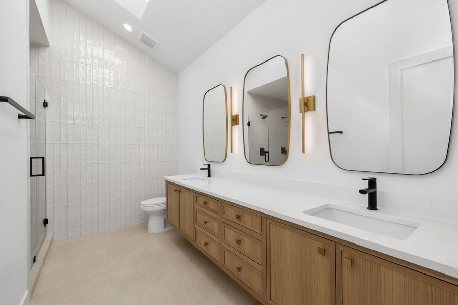 Bathroom featuring double vanity, a stall shower, lofted ceiling, light tile patterned floors, and recessed lighting Bathroom featuring double vanity, a stall shower, lofted ceiling, light tile patterned floors, and recessed lighting