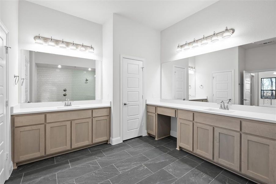 Bathroom with a stall shower, two vanities, and dark marble finish floors Bathroom with a stall shower, two vanities, and dark marble finish floors