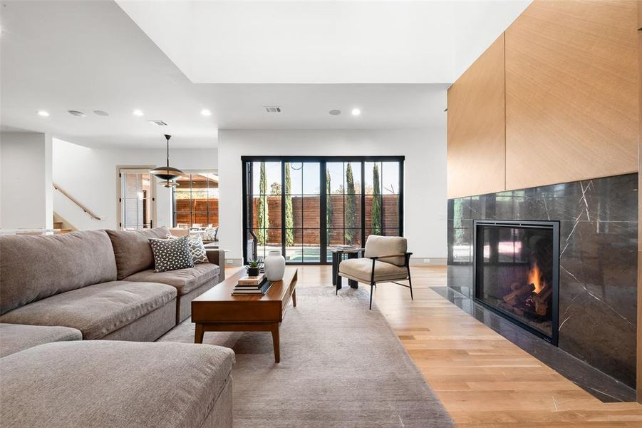 Living area featuring a tiled fireplace, light wood-style floors, and recessed lighting