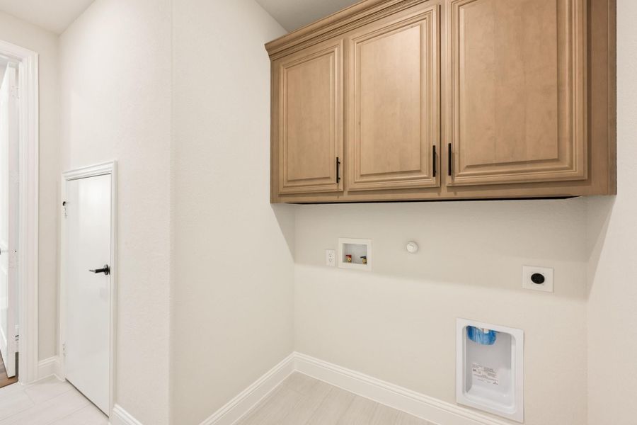 Laundry room with wood upper cabinets, washer hookups, and gas dryer connection on white walls Laundry room with wood upper cabinets, washer hookups, and gas dryer connection on white walls
