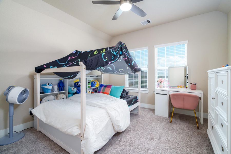 This inviting bedroom features plush carpet, windows for natural light, and a sleek modern ceiling fan for added comfort. This inviting bedroom features plush carpet, windows for natural light, and a sleek modern ceiling fan for added comfort.