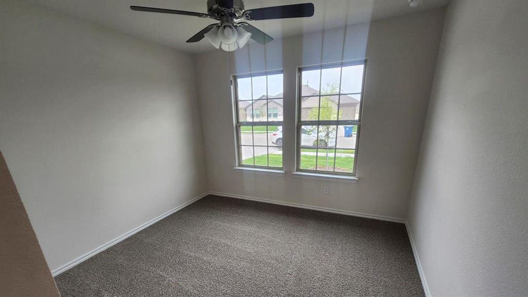 Room featuring two large windows, neutral-toned carpeting, and a ceiling fan with integrated lighting