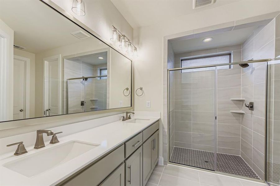 Full bathroom with a shower stall, double vanity, light tile patterned floors, and recessed lighting