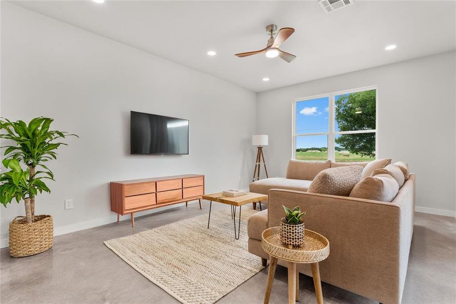 Living room featuring recessed lighting, ceiling fan, and concrete flooring Living room featuring recessed lighting, ceiling fan, and concrete flooring