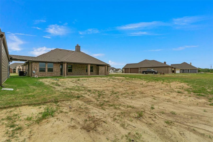 Expansive outdoor space featuring a partial green lawn and open ground