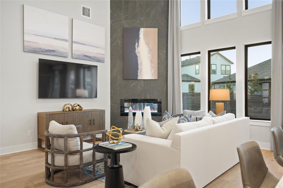 Living room featuring healthy amount of natural light, wood finished floors, a fireplace, and a high ceiling