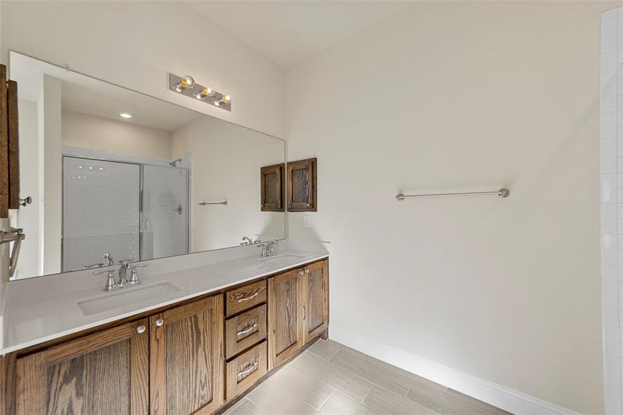 Bathroom featuring tile patterned flooring, vanity, and an enclosed shower