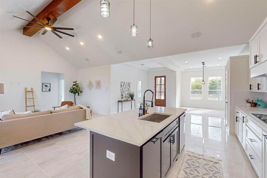 Kitchen featuring an island with sink, white cabinetry, pendant lighting, and beam ceiling