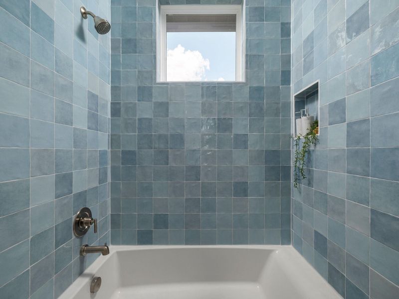 Bathe in tranquility with this tub and shower, featuring an alcove window for natural light.