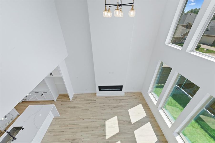 Unfurnished living room with a high ceiling, light wood-style floors, a fireplace, and a chandelier