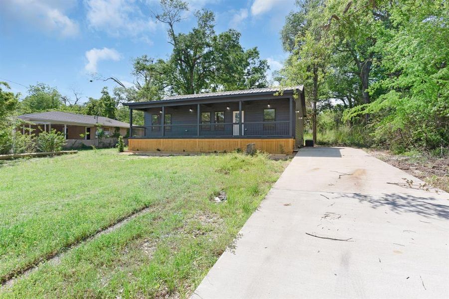 View of front of house with driveway, a porch, metal roof, and a front yard View of front of house with driveway, a porch, metal roof, and a front yard