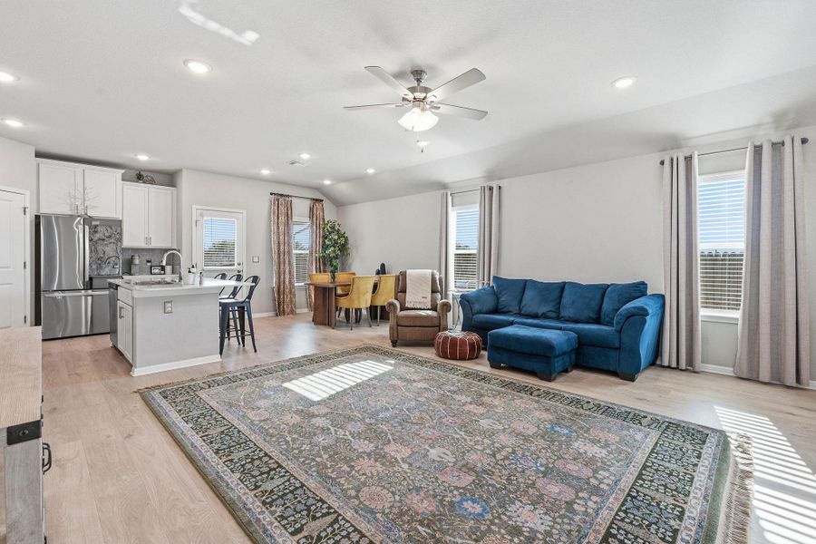 Living room with light wood-style flooring, ceiling fan, vaulted ceiling, and recessed lighting Living room with light wood-style flooring, ceiling fan, vaulted ceiling, and recessed lighting