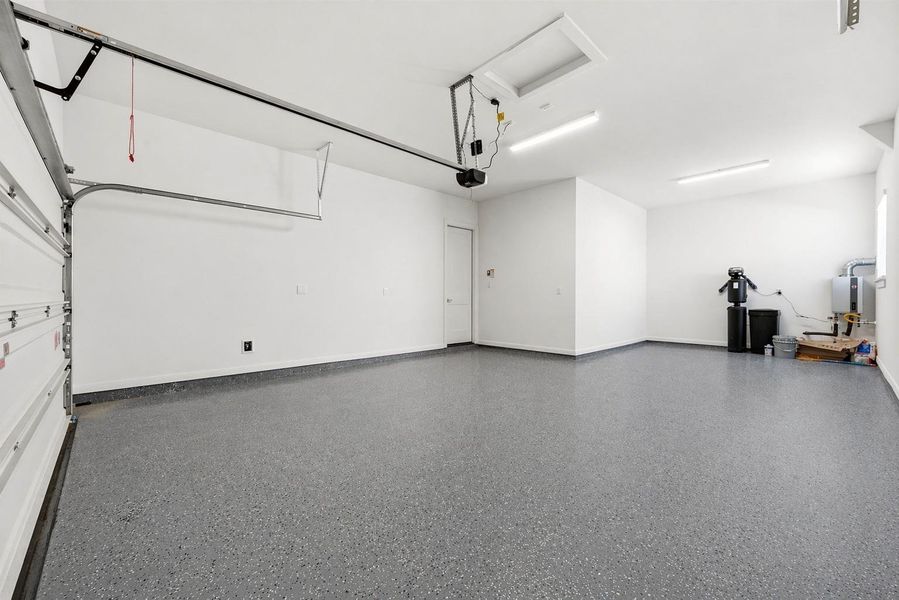 This oversized 3-car tandem garage features a pristine epoxy-coated floor and ample space for vehicle storage, organization, and home maintenance systems. Outfitted with a water softener system and tankless water heater, plus ample room for storage, hobbies, or a workshop setup.