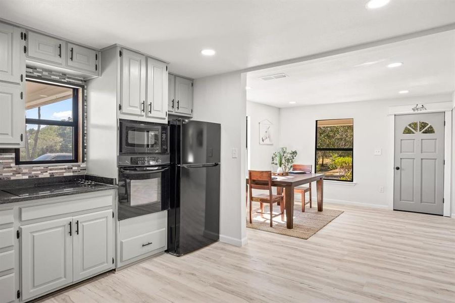 Kitchen featuring black appliances, tasteful backsplash, and light hardwood / wood-style flooring