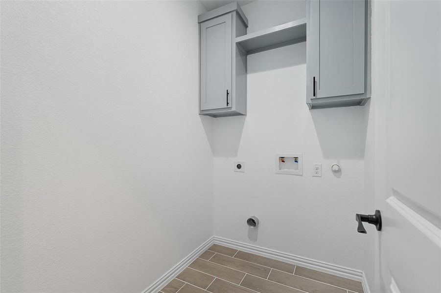 Laundry area featuring wood finish floors, cabinet space, washer hookup, hookup for an electric dryer, and gas dryer hookup Laundry area featuring wood finish floors, cabinet space, washer hookup, hookup for an electric dryer, and gas dryer hookup