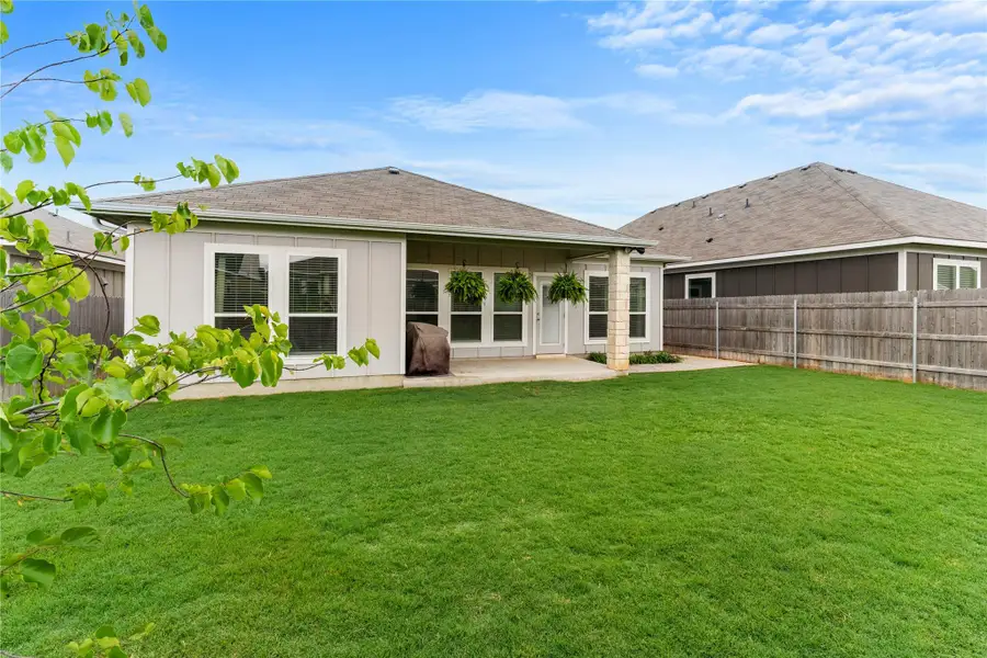 A well-maintained lawn extends to a cozy covered patio space, ideal for outdoor relaxation. A well-maintained lawn extends to a cozy covered patio space, ideal for outdoor relaxation.
