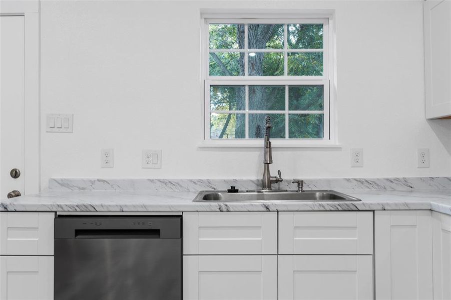 Kitchen featuring white cabinets, dishwasher, and light stone counters