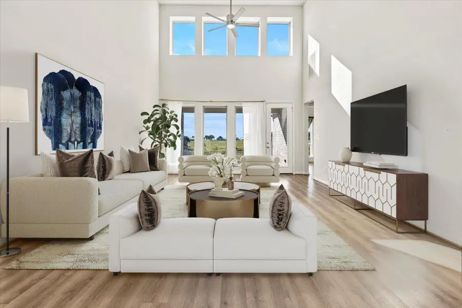 Living area featuring light wood-style flooring, healthy amount of natural light, ceiling fan, and a towering ceiling. Virtual Staging Added. Living area featuring light wood-style flooring, healthy amount of natural light, ceiling fan, and a towering ceiling. Virtual Staging Added.