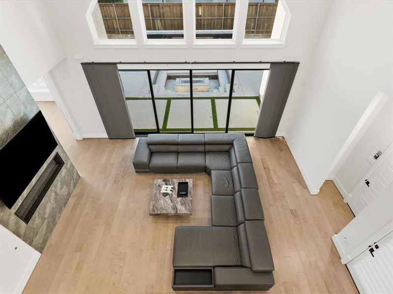 Two-story living area featuring wood-finish flooring and a tiled fireplace surround Two-story living area featuring wood-finish flooring and a tiled fireplace surround