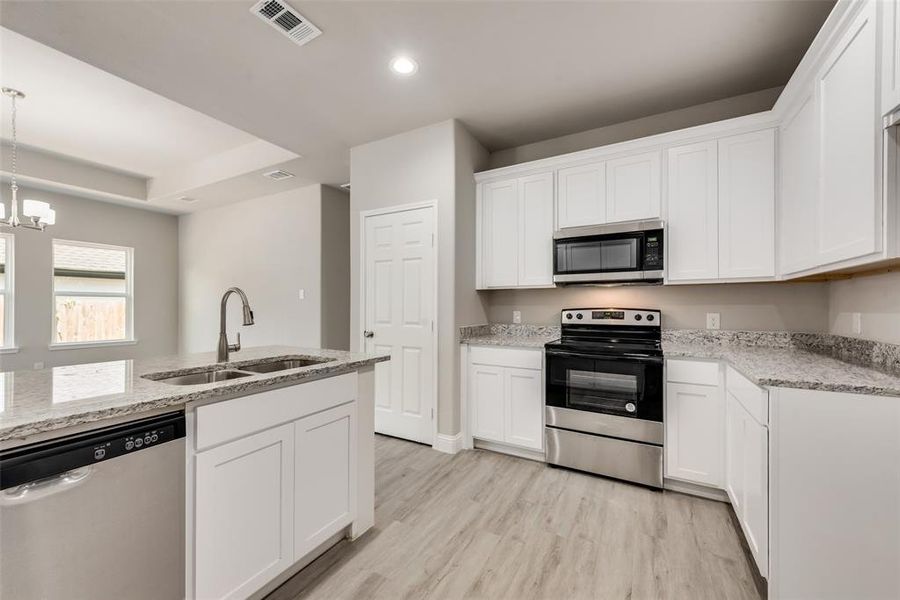 Kitchen with light hardwood / wood-style floors, white cabinetry, sink, and stainless steel appliances