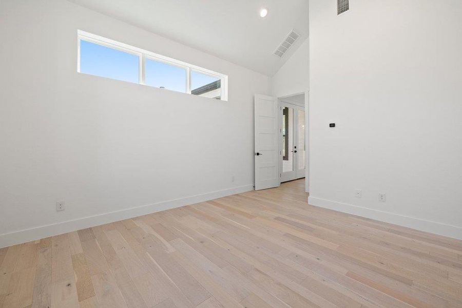 Empty room with light wood-type flooring, vaulted ceiling, and recessed lighting