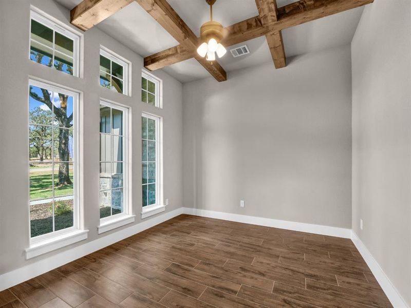 Unfurnished room with beamed ceiling, wood finish floors, coffered ceiling, and ceiling fan