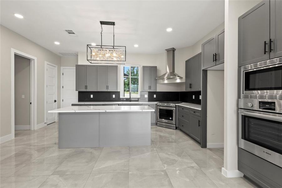 A chef-inspired kitchen featuring a large gathering island, double ovens, 5-burner gas range, and oversized walk-in pantry.