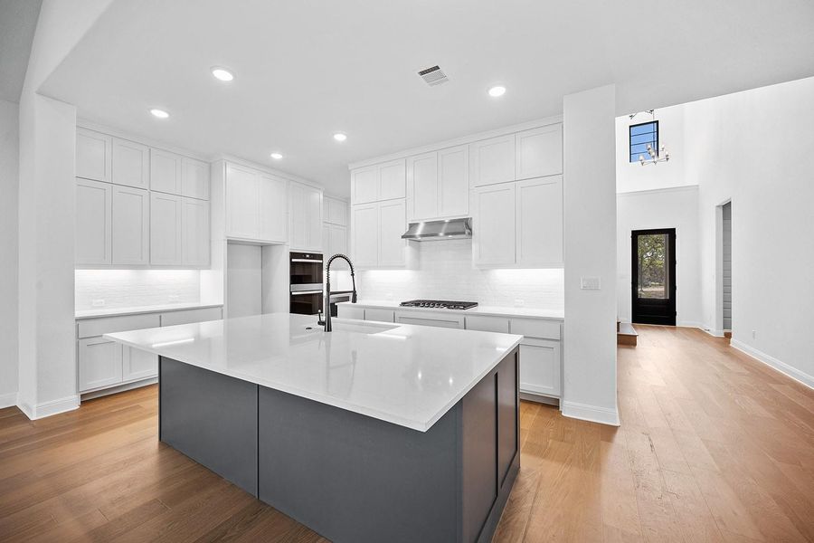 Kitchen with a sink, backsplash, light wood-style floors, white cabinetry, and recessed lighting Kitchen with a sink, backsplash, light wood-style floors, white cabinetry, and recessed lighting