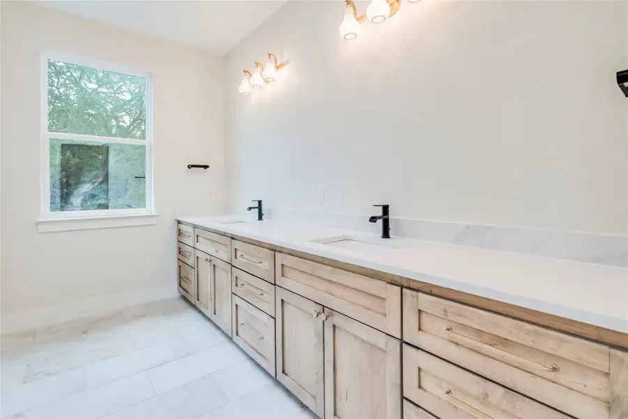 Bathroom with double vanity and light tile patterned floors