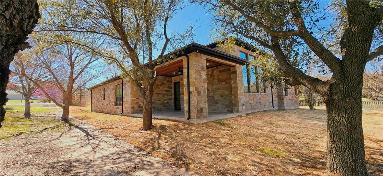 View of front of house featuring stone siding, a patio area, and a front lawn View of front of house featuring stone siding, a patio area, and a front lawn