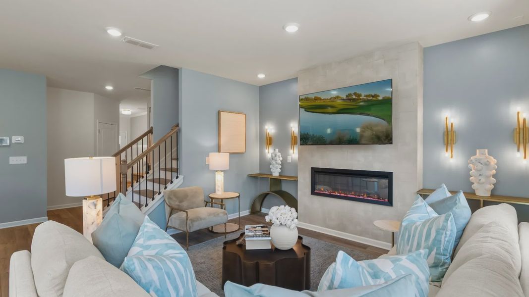 Spacious family room with electric fireplace, large windows, and open layout in new construction townhome.