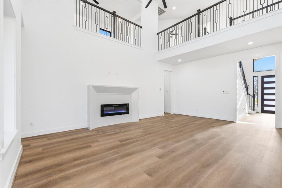 The spacious living room features soaring 21-foot ceilings, a large ceiling fan, and a sleek electric fireplace.