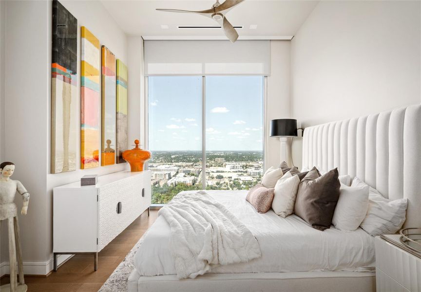 Secondary bedroom featuring hardwood floors, Tailored motorized blackout shades and a floor-to-ceiling window that fills the space with natural light.