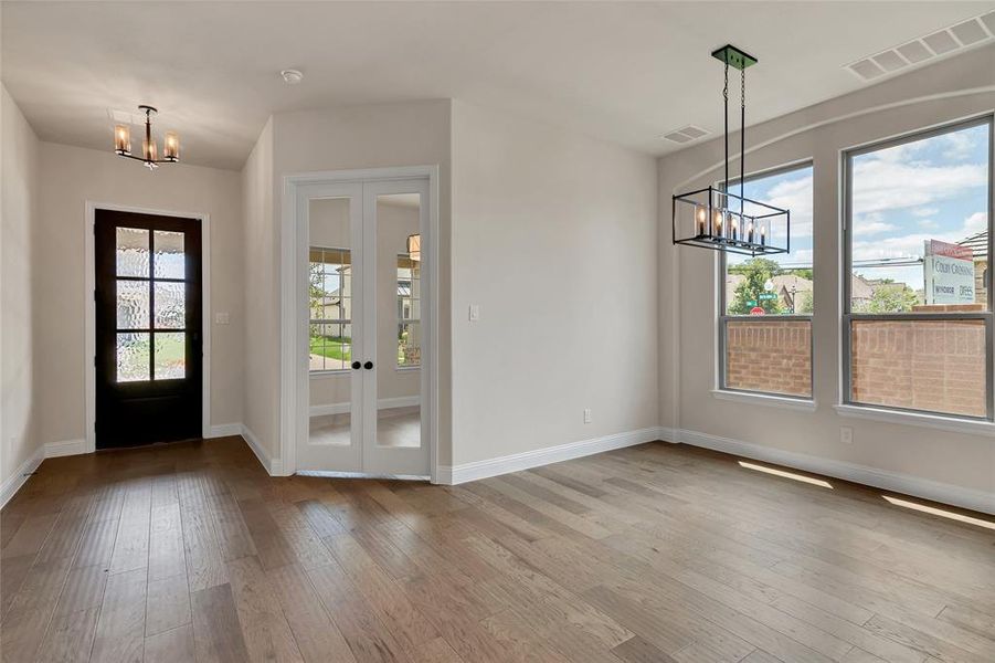 Foyer featuring hardwood / wood-style flooring, french doors, and a chandelier