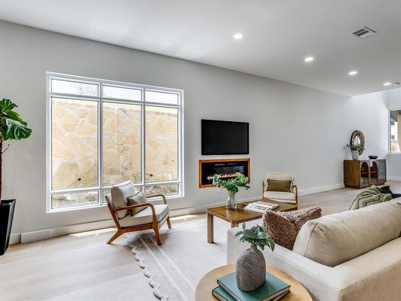 Living area featuring light wood-finish flooring, recessed lighting, and an integrated electric fireplace with a wood surround Living area featuring light wood-finish flooring, recessed lighting, and an integrated electric fireplace with a wood surround